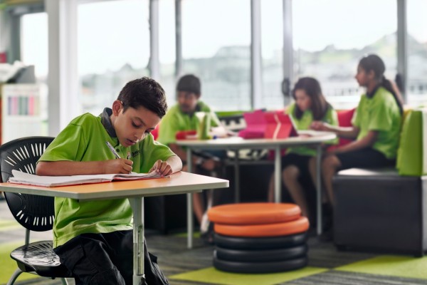 school boy in classroom writing at desk