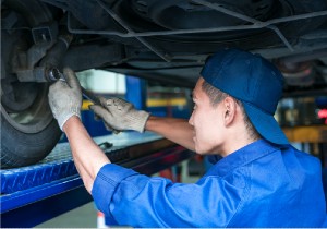 Mechanic standing under a vehicle fixing a tyre